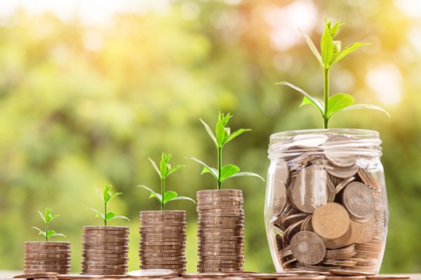 money in four glass jars with plants growing from the money