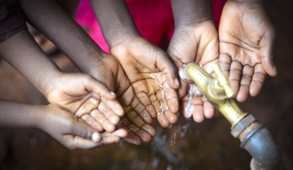 Children's hands waiting for water from a water tap