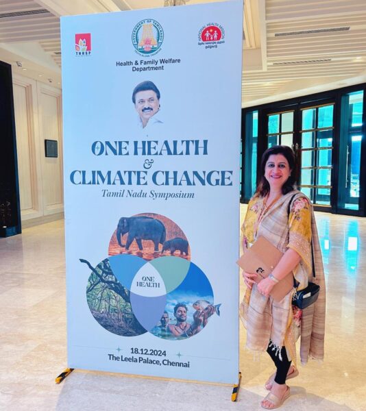 Woman posing by The One Health and Climate Change Hub poster. Photo: Privat
