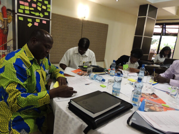 Three men sitting at a table with computers discussing and working. This at an early network meeting in the African region.