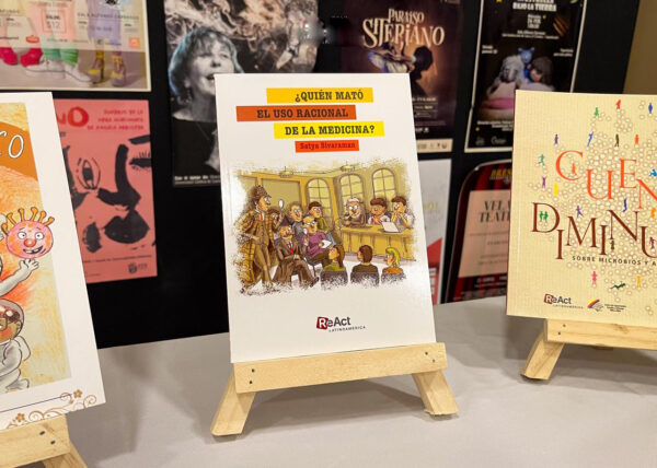 A display of illustrated ReAct Latin America publications, including the book Who Killed the Rational Use of Medicine?, presented on easels against a backdrop of other illustrated materials.